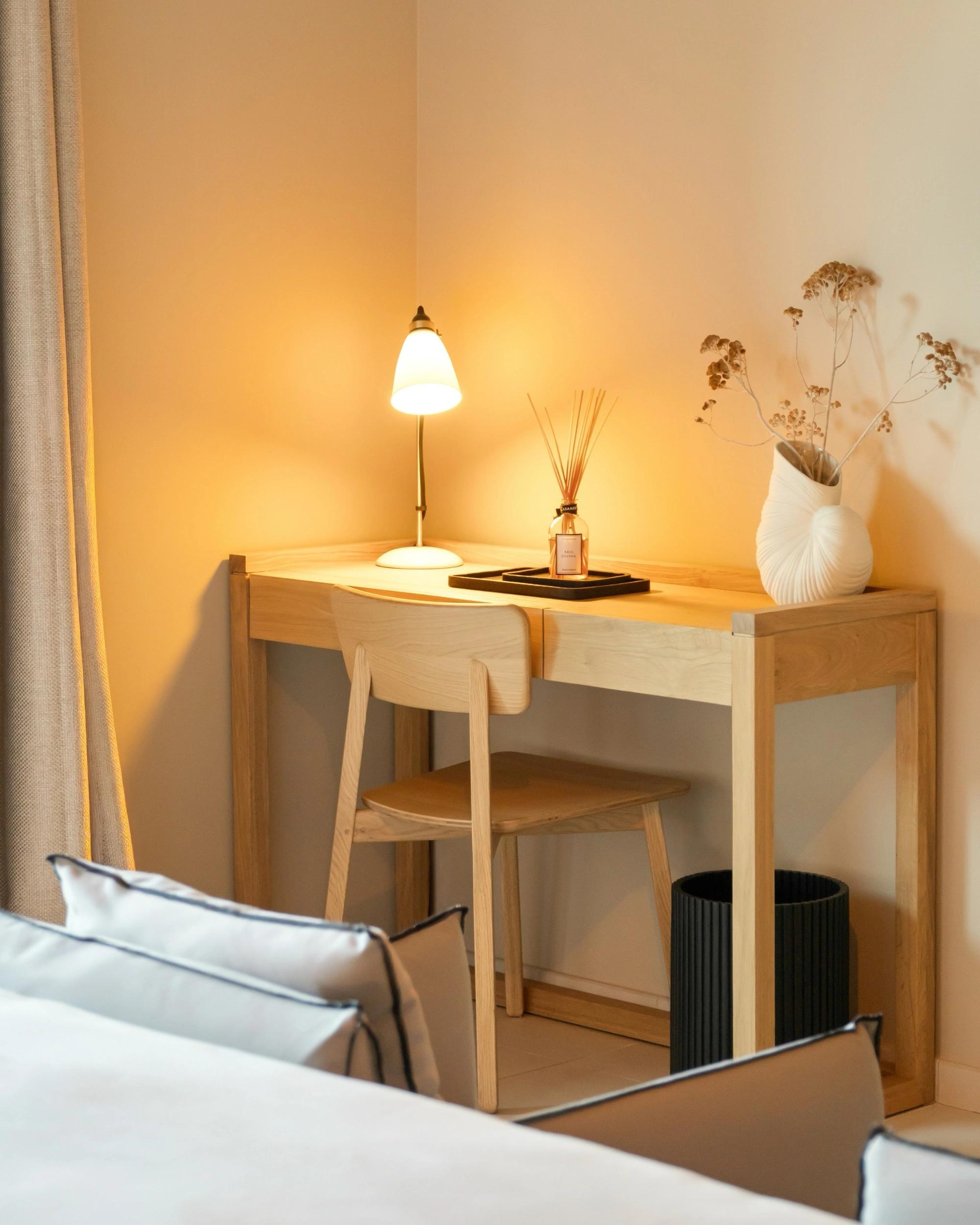Bureau en bois clair et lampe allumée dans une suite